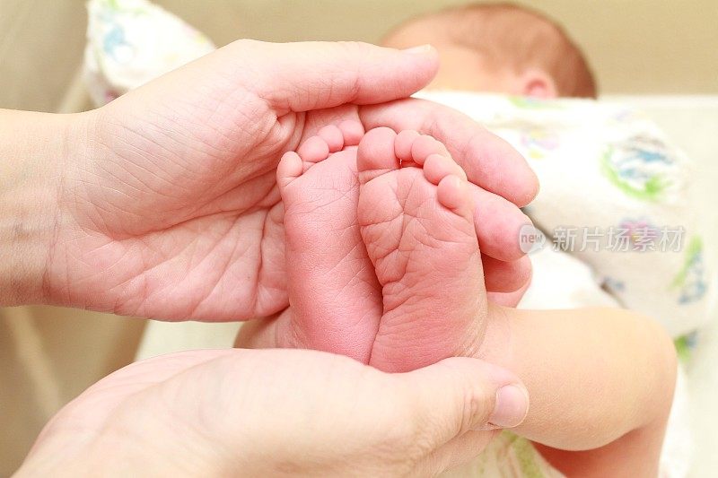 Baby feet in mother hands. Tiny Newborn Baby's feet on female Shaped hands closeup. Mom and her Child. Happy Family concept. Beautiful conceptual image of Maternity.